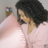 curly hair girl holding pink satin pillowcase